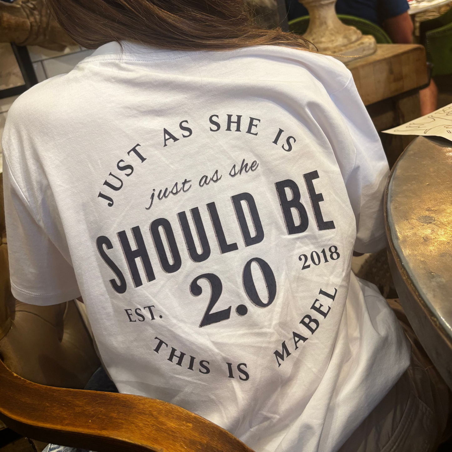 Person wearing a white t-shirt with text in an indoor setting