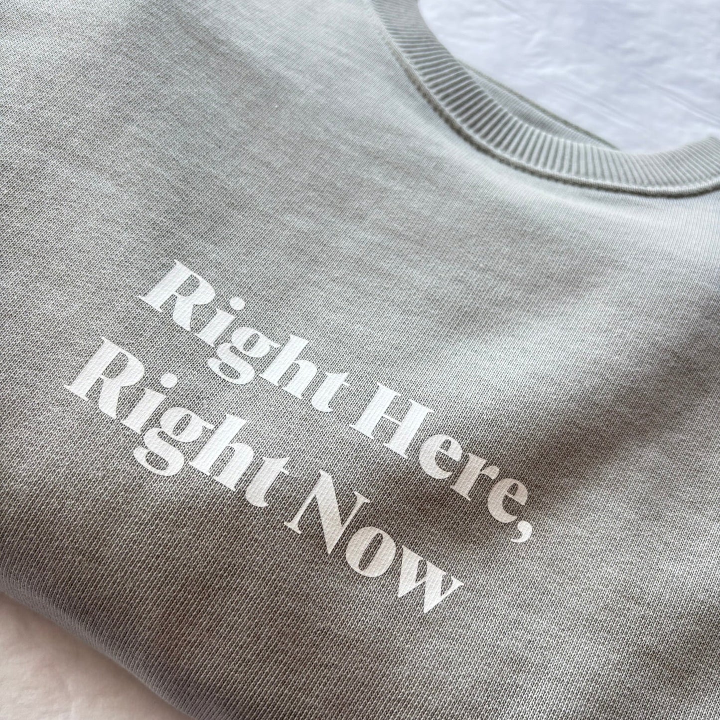 Gray sweatshirt with 'Right Here, Right Now' text on a light background