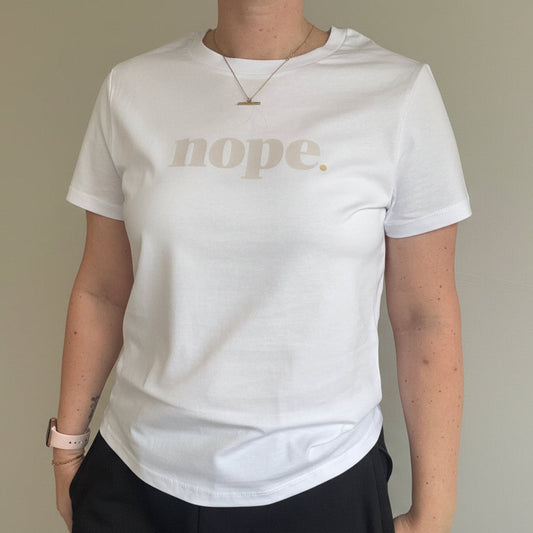 Person wearing a white t-shirt with 'nope' printed on it, standing indoors.
