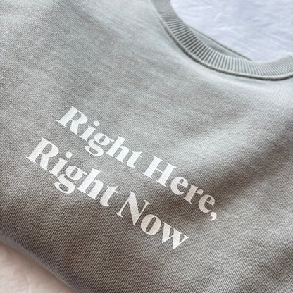 Gray sweatshirt with 'Right Here, Right Now' text on a light background
