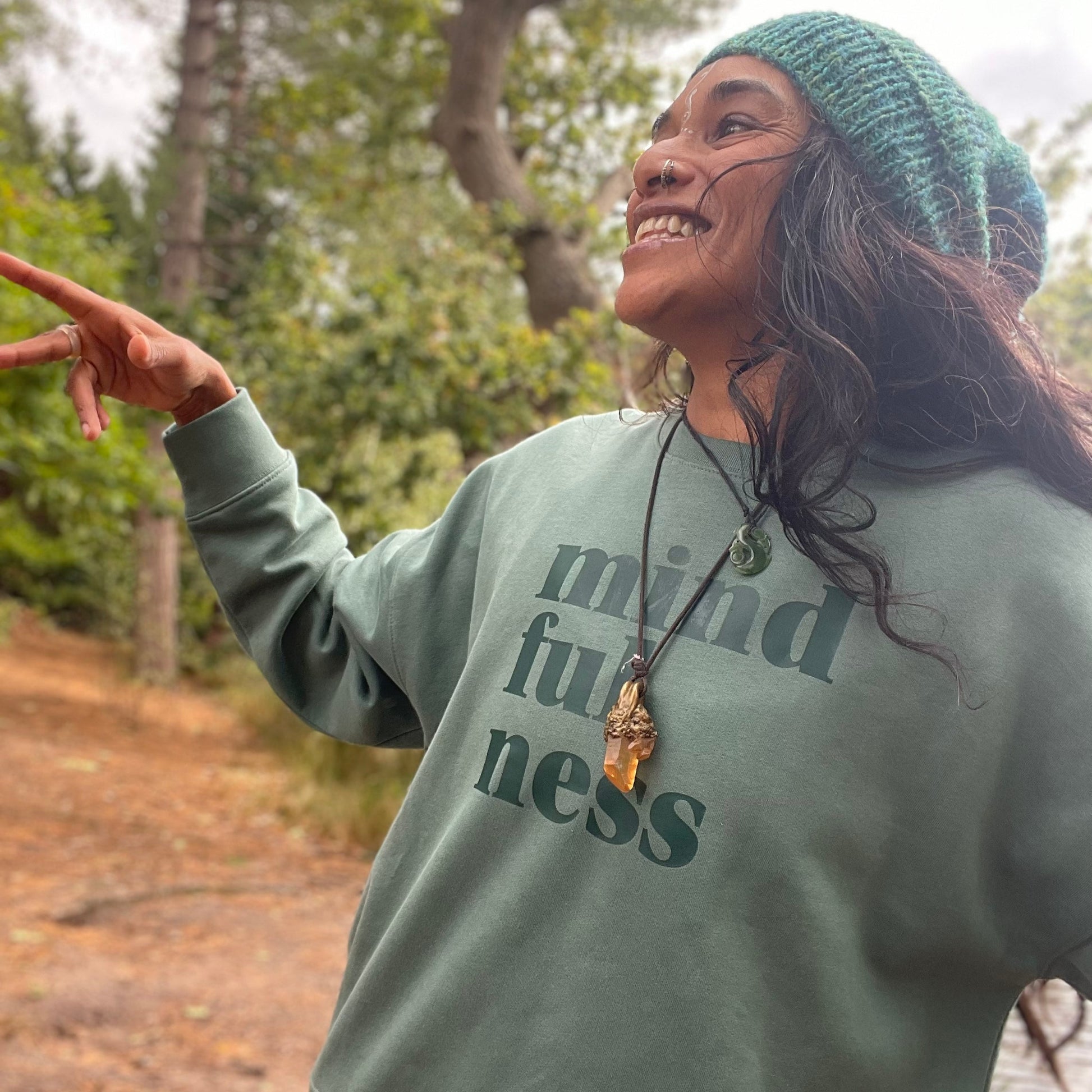 Person wearing a green sweatshirt with 'mindfulness' text outdoors