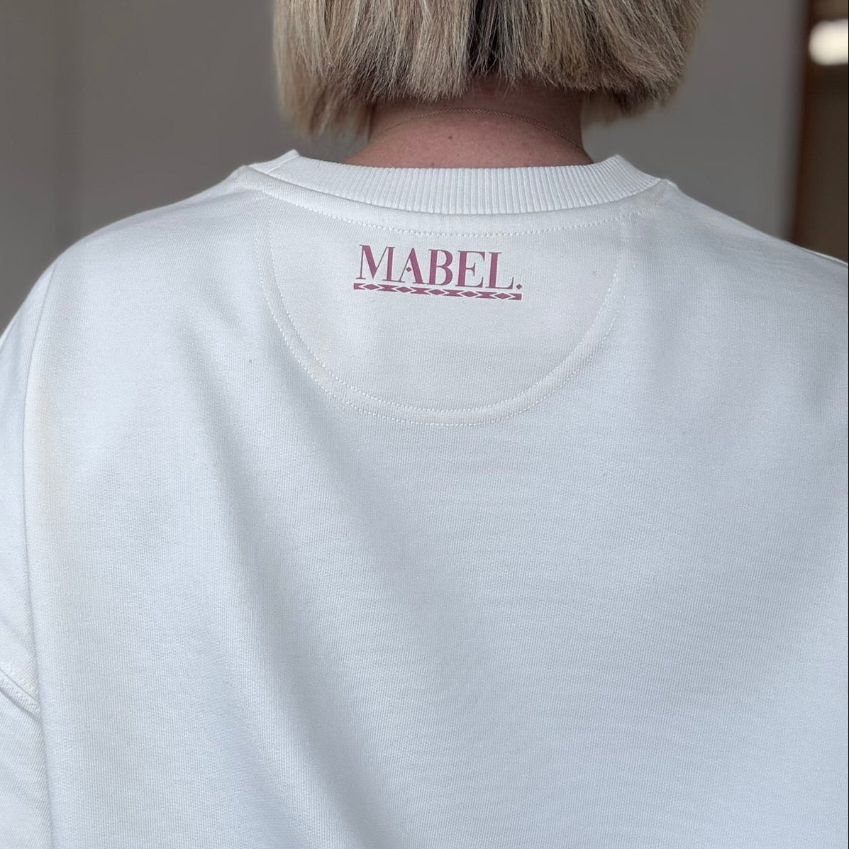 Person wearing a white sweatshirt with 'MABEL' branding on the back.