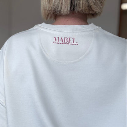 Person wearing a white sweatshirt with 'MABEL' branding on the back.