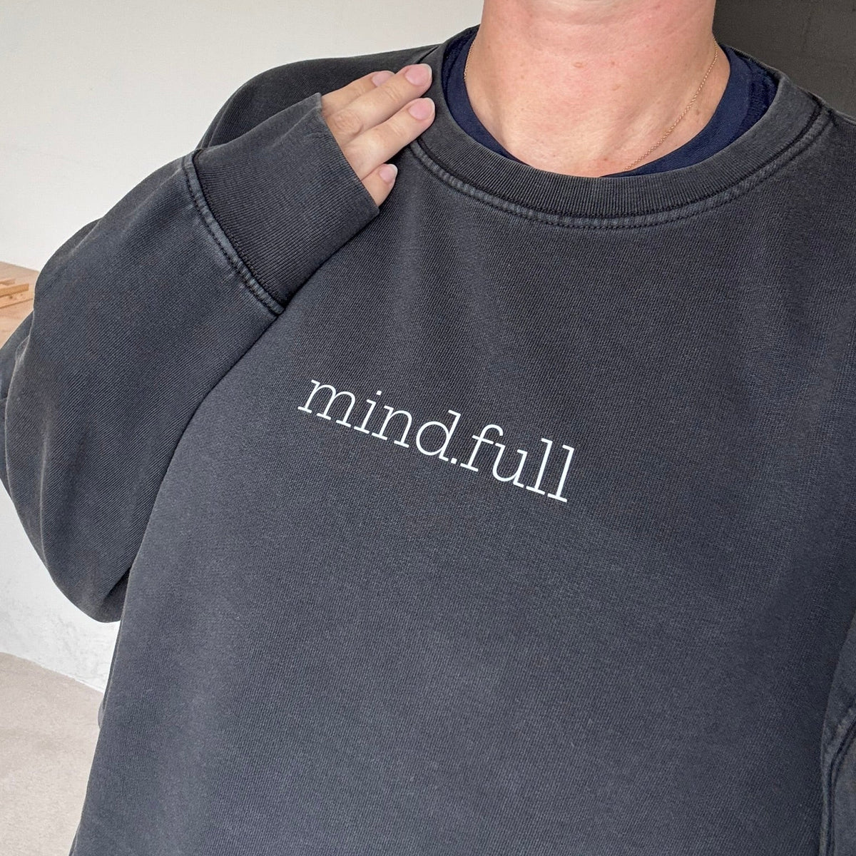A close-up of a person wearing a faded black crewneck sweatshirt with the words 'mind.full' printed in white lowercase serif text across the chest.