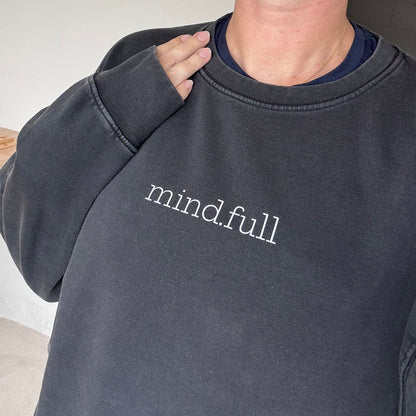 A close-up of a person wearing a faded black crewneck sweatshirt with the words 'mind.full' printed in white lowercase serif text across the chest.