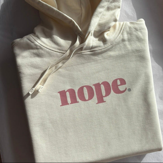 Folded hoodie with 'nope' text on a white surface