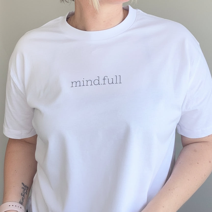 Person wearing a white t-shirt with 'mindful' text against a plain background