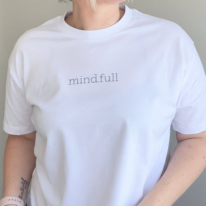 Person wearing a white t-shirt with 'mindful' text against a plain background